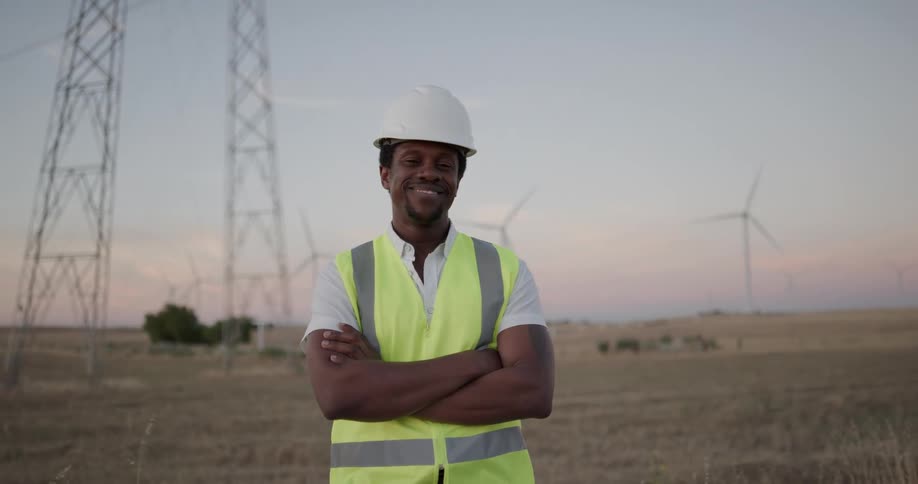 An employee standing on a wind farm poses for a photo