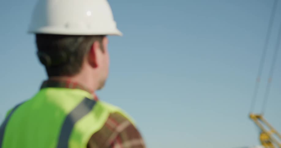 A construction worker flies a drone over a construction site