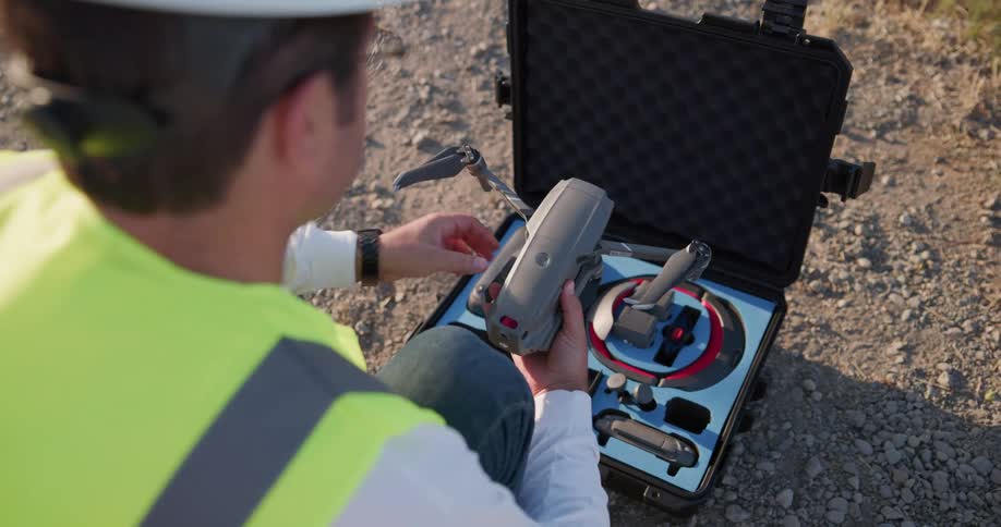 A man kneels to unpack a remote controlled drone from its carrying case