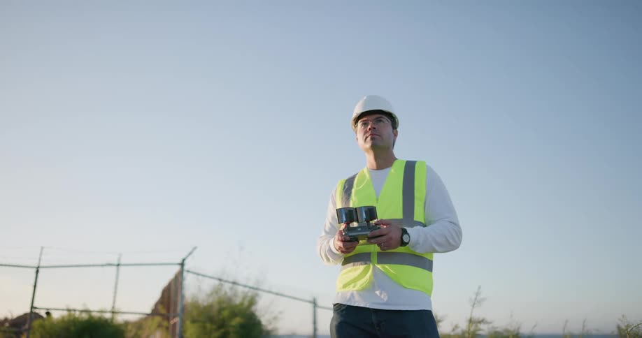 Construction workers flies a drone using a remote control on a construction site
