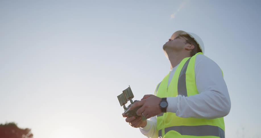 A construction worker uses a drone to shoot footage outdoors