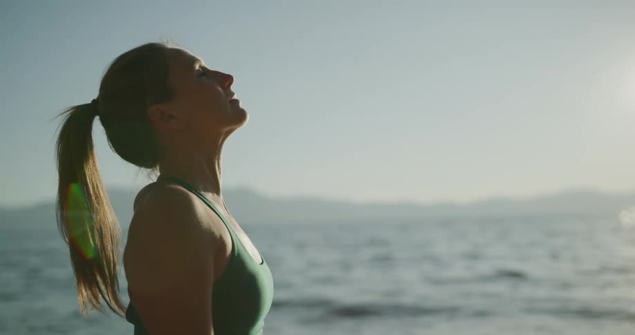 A woman raises her head as she performs yoga on the beach