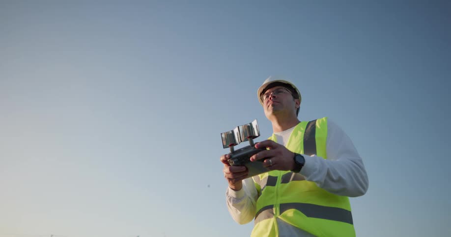 Man in high visibility vest and hard hat holding large controller