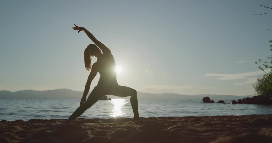 A woman is stretching and doing yoga at the beach
