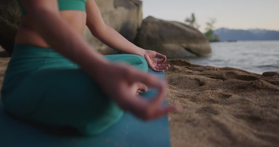 A woman sitting on the edge of a river meditating