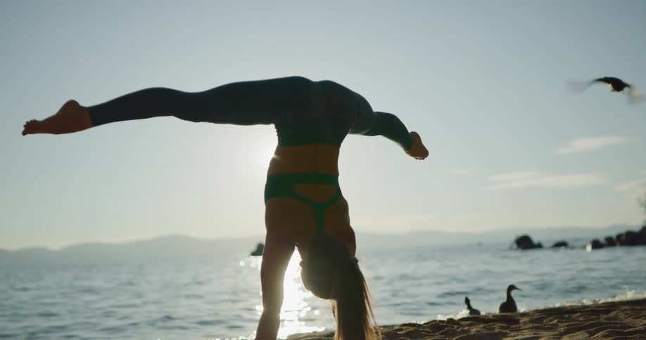 A woman is doing yoga on the beach at dusk