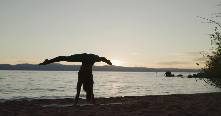 A woman is doing yoga at the beach