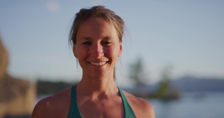 Middle aged woman with a ponytail faces the camera smilingly with eye contact