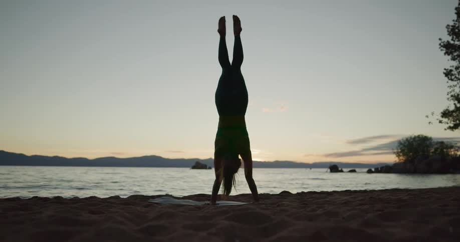 A woman is doing yoga at the beach