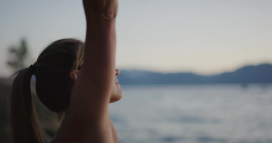 A woman practices yoga near a body of water