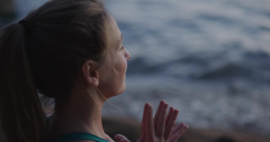A woman is doing a yoga pose outdoors at the beach