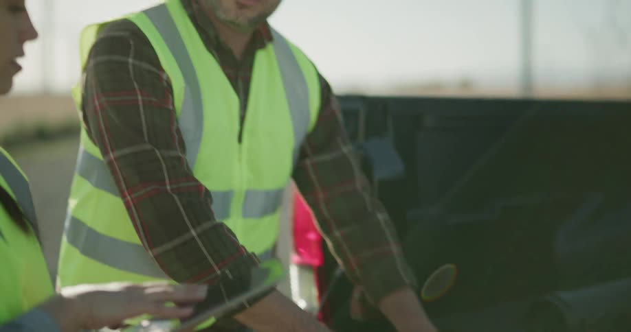 A man and woman rolling up blueprints in the bed of a truck