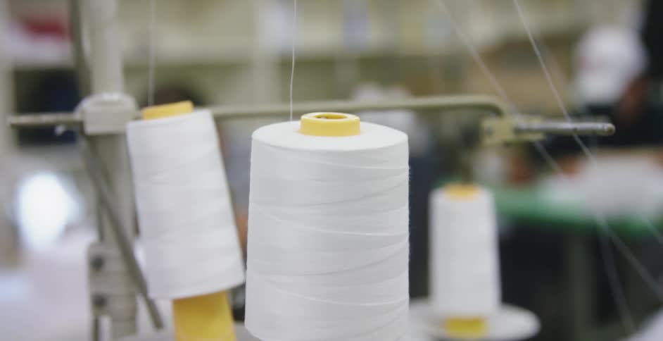 Cones of white thread feeding a sewing machine on a workhsop