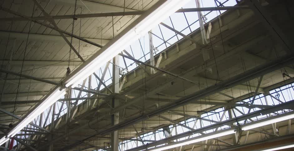 Fluorescent lamps hanging from the high ceiling of a warehouse at day