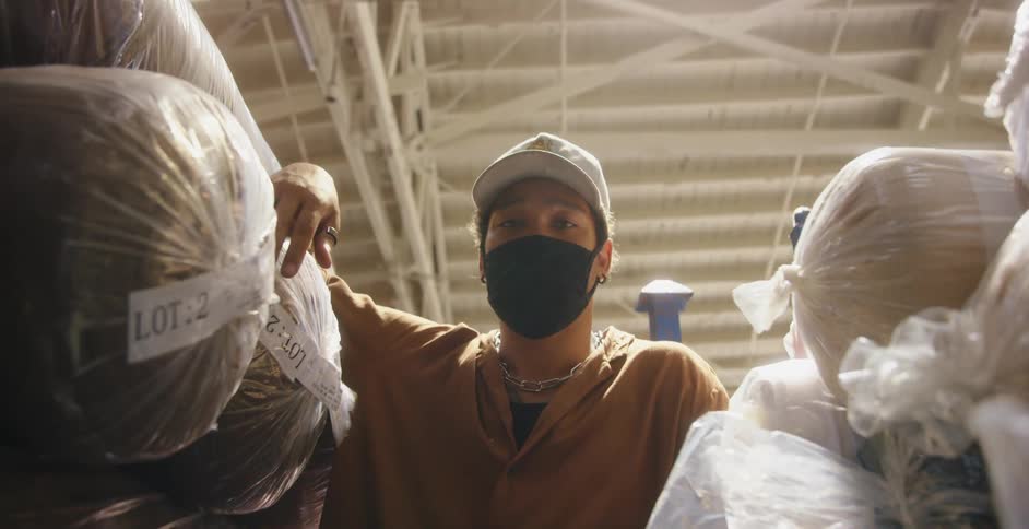 A man is leaning on some bags in the warehouse