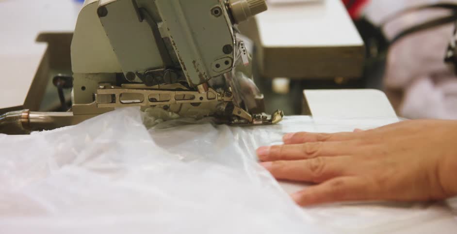 Seamstress uses an industrial sewing machine to sew plastic garments