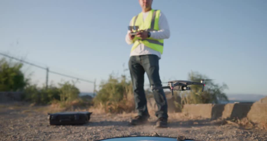 A man in a hard hat controls a drone