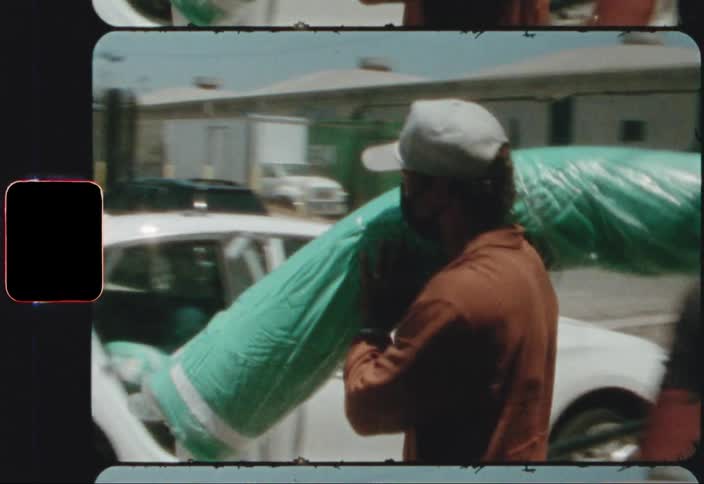 A man carries a carpet over to his car