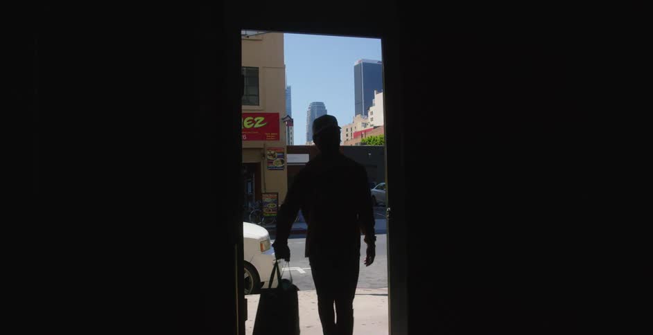 Man wearing a face mask walks into a dark building from the street