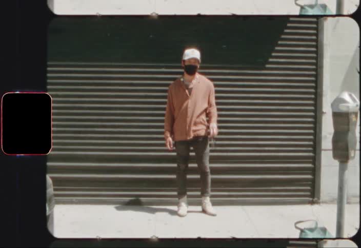 Young man wearing face mask and baseball hat standing on a street in the city