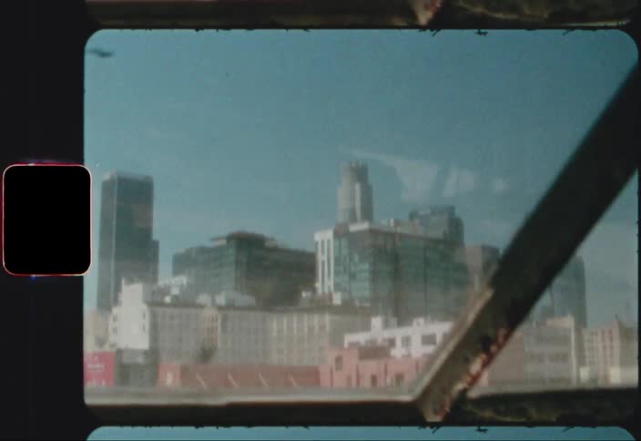 Skyline of a city under a blue sky caught on film from a window