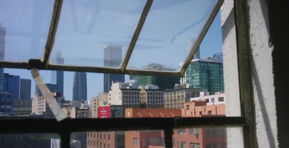 An urban skyline is visible through an open window