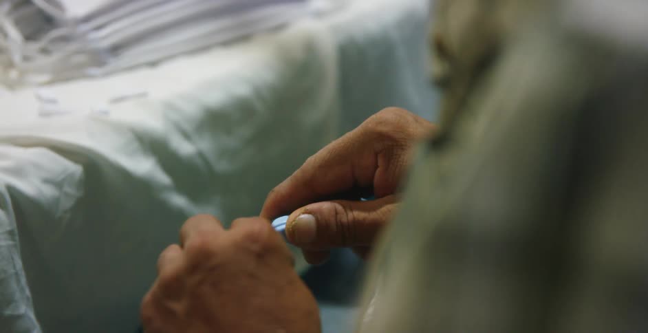 Worker trims the excess threads and fabric from a face mask on a factory