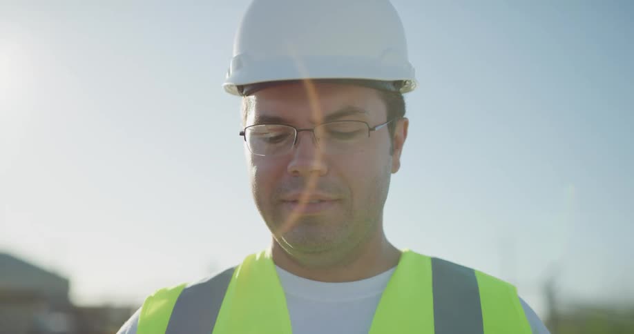 A man in a hard hat looks around a job site and talks
