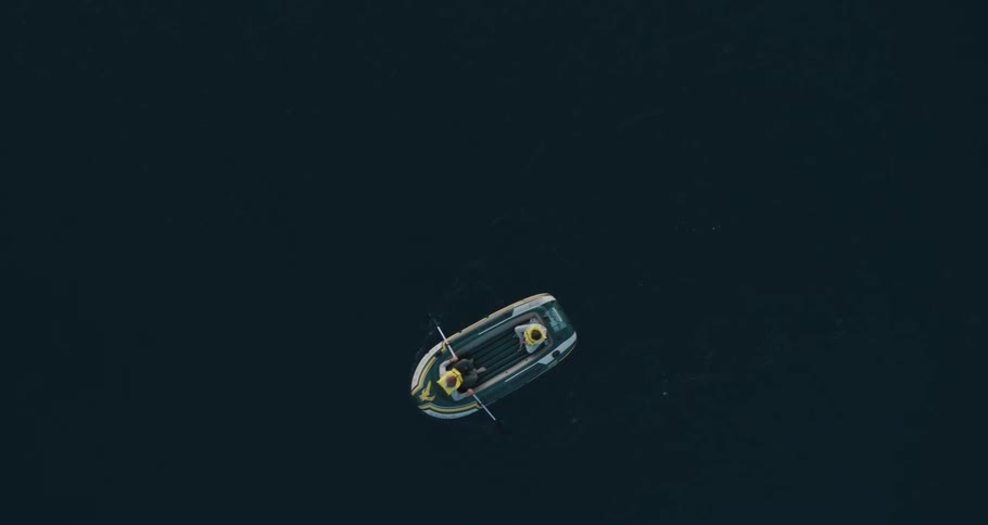 Aerial view of two people rowing with oars on an inflatable boat in a lake
