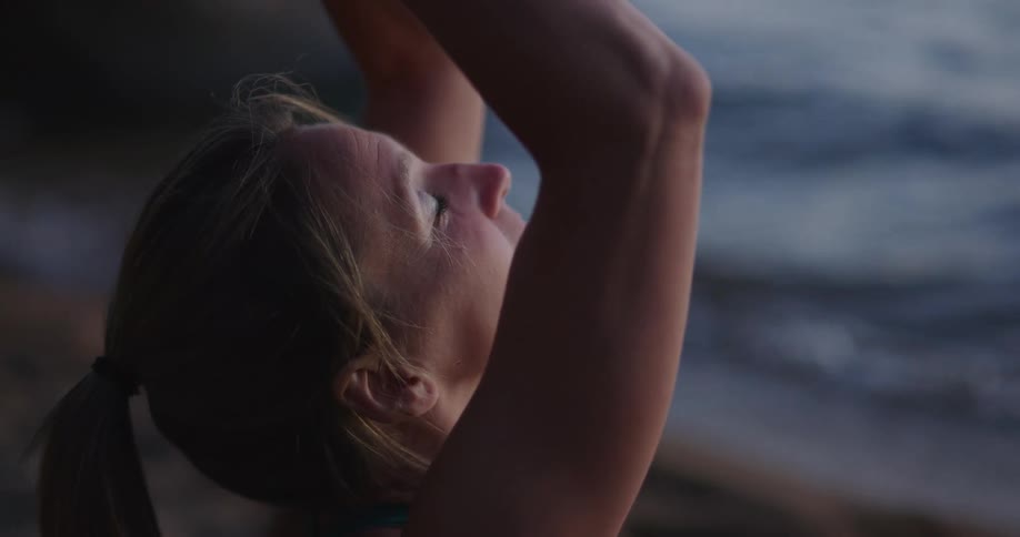 A woman does yoga on the beach during the day