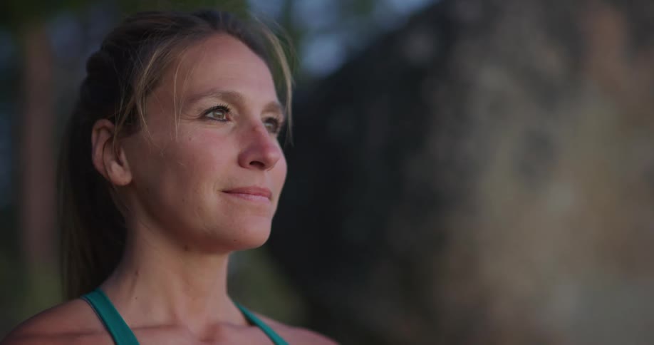 Side view of a blonde middle aged woman looking into space smilingly