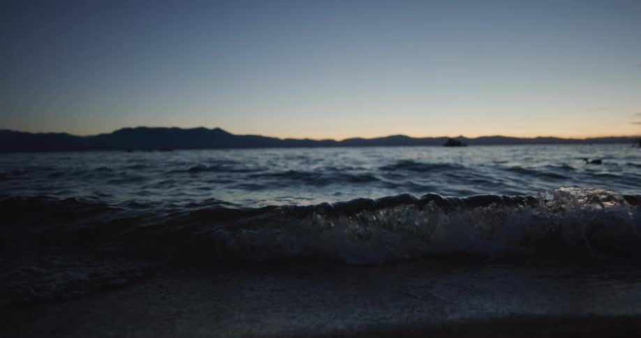 A lake with waves with a mountain range the sky and clouds in the background