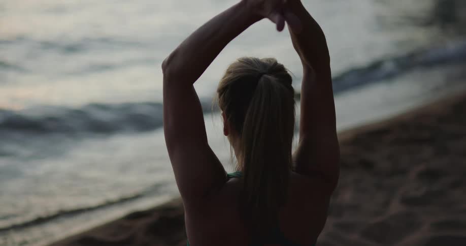 A woman does yoga on the beach