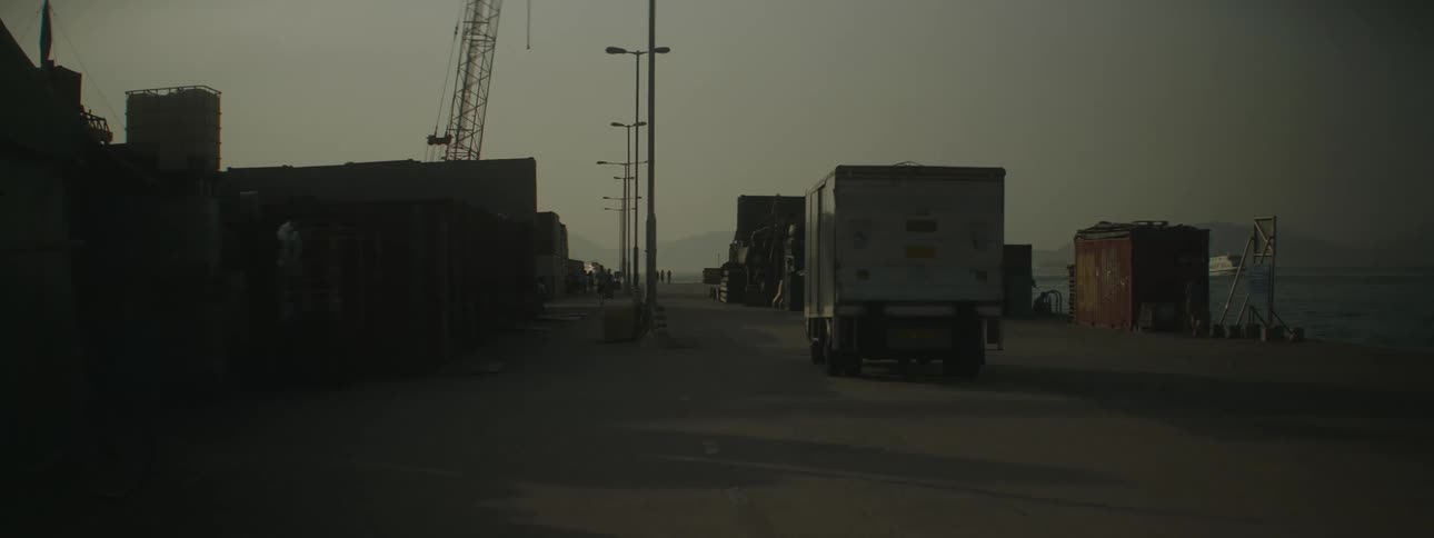 A cargo truck drives down a road near water