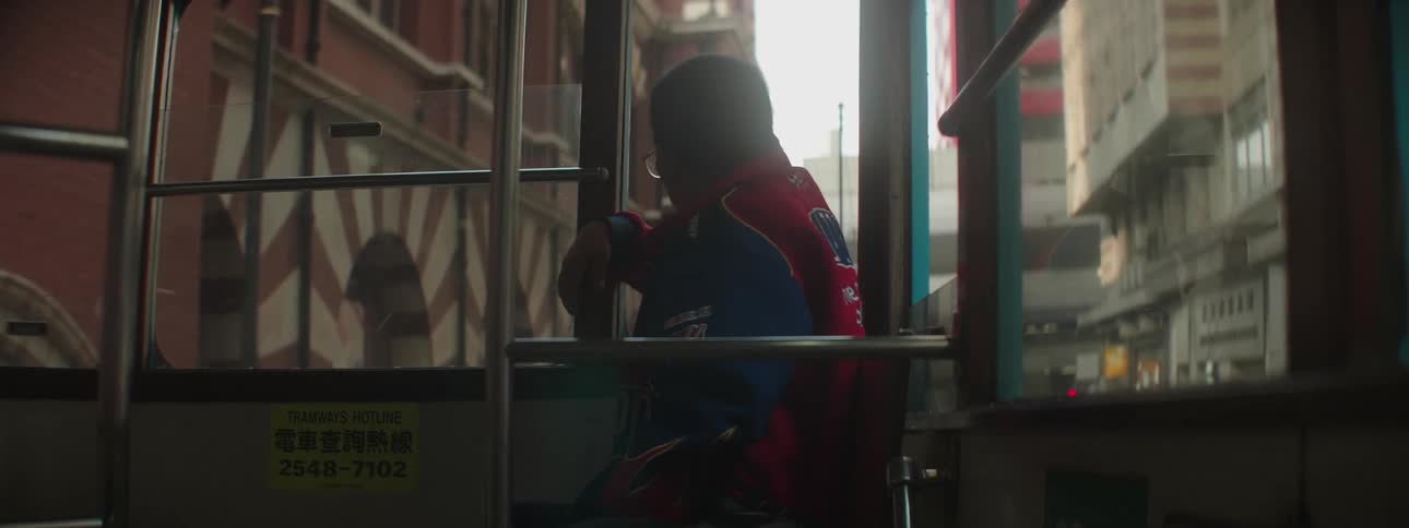 A man sits on a tram car that travels through the street