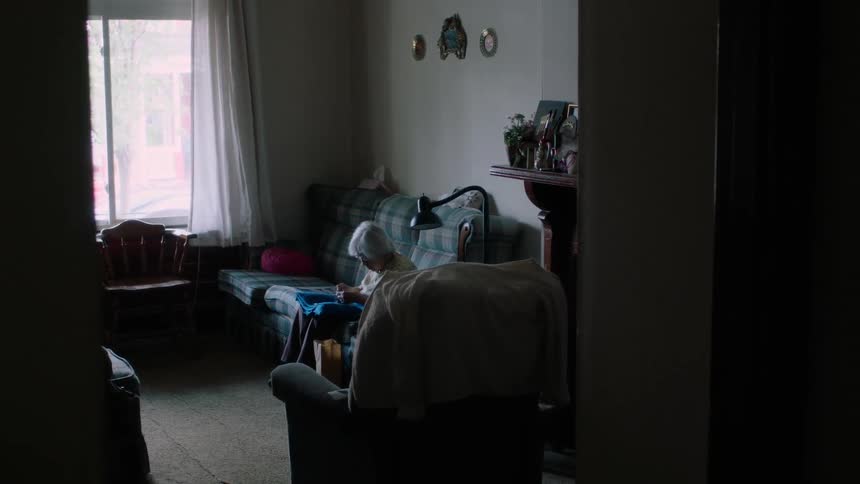 A woman is sitting on the couch knitting