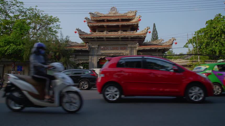 Traffic of a busy city street flows in front of the entrance of a temple in malaysia