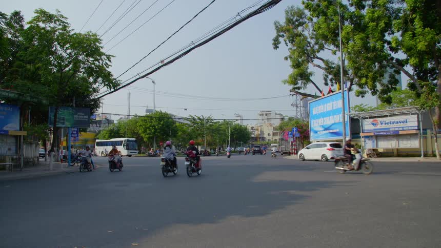 Traffic on a street in a town with cars and people on motor bikes