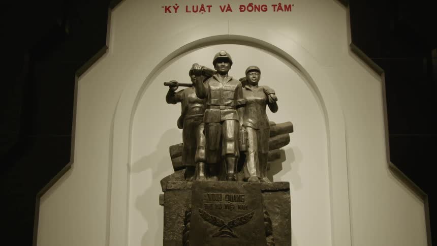 A bronze statue on a pedestal with a wall in the background
