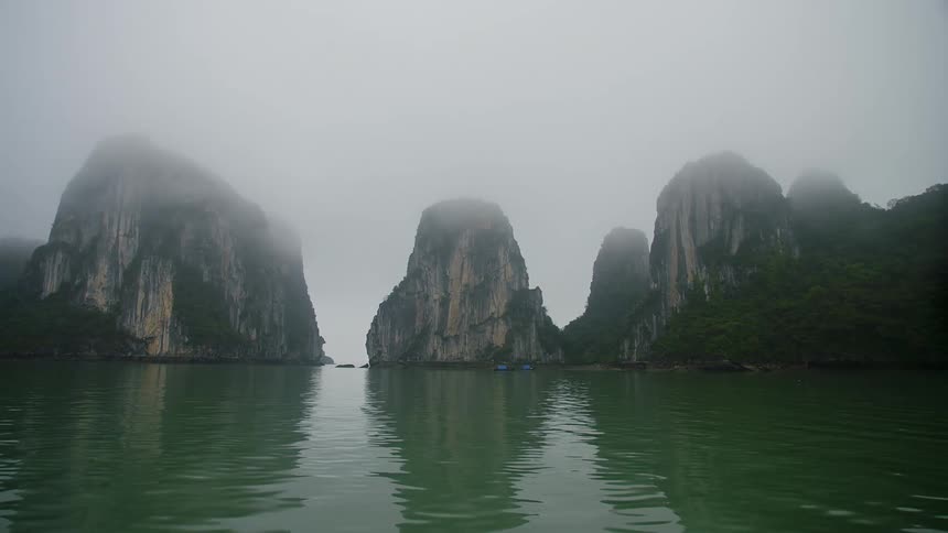 Peaks of mountains peak out of the ocean on a foggy day