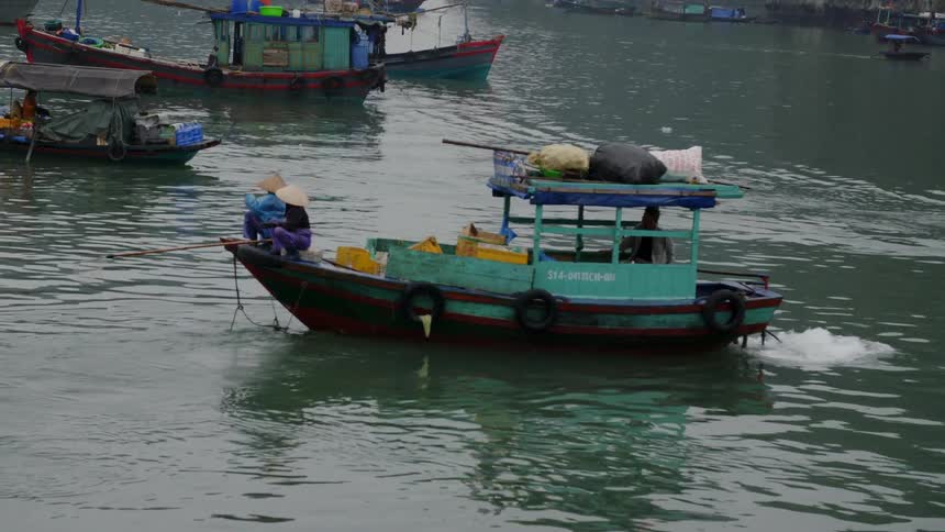 Two people sit calmly on a small boat on a third world nation river