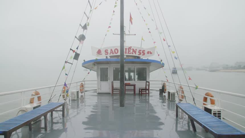 A ship moves on calm water on a foggy day