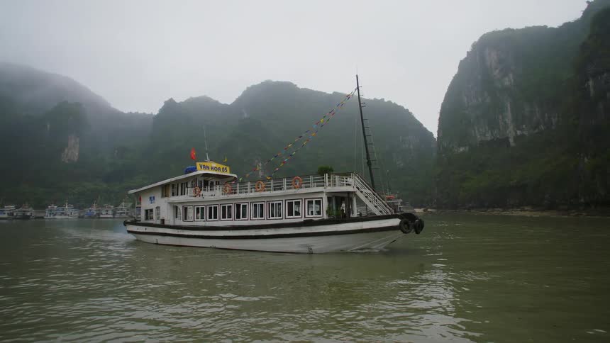 A ferry moves across a large river along side tall mountains