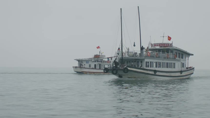 Boat loaded with passengers passes another boat on the ocean