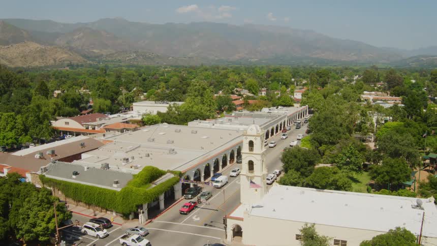 A small town with roads and traffic near mountains and trees