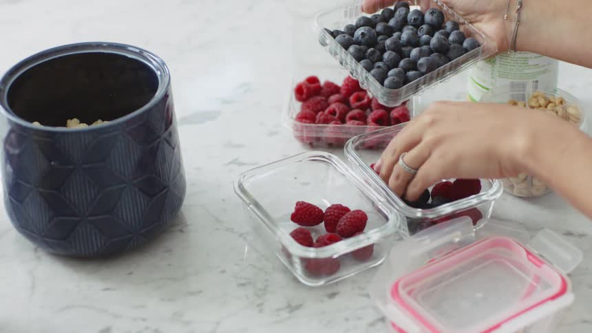 Woman stores different types of berries on glass containers at home