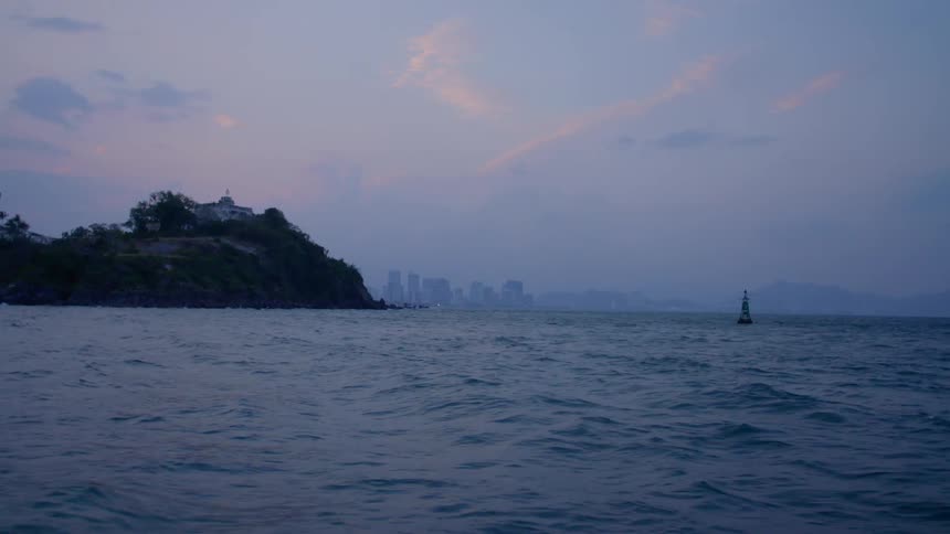 Skyline of a far away city on the coast of the ocean at sunset