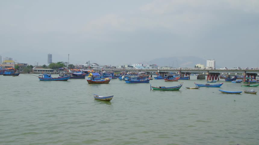 Boats in a lake with people riding bikes across a bridge
