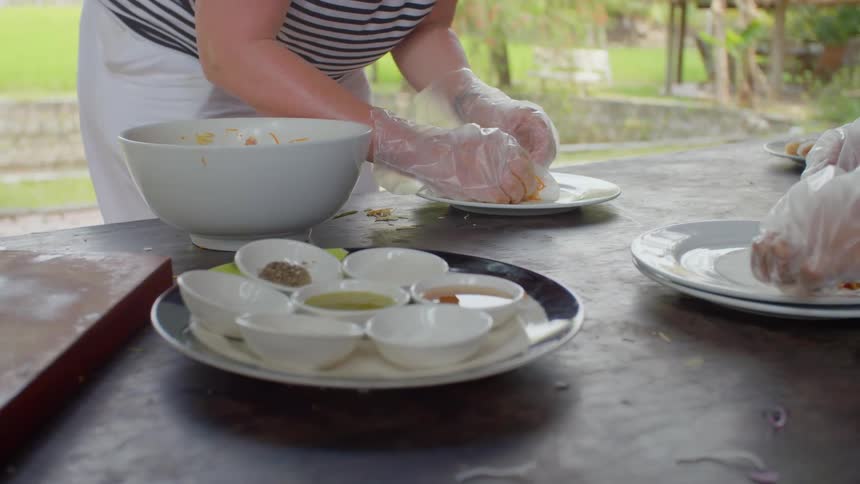 Two women prepare food on a table outdoors
