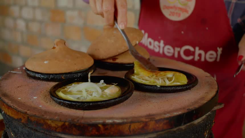 A chef cooking food in cast iron pots with a spatula